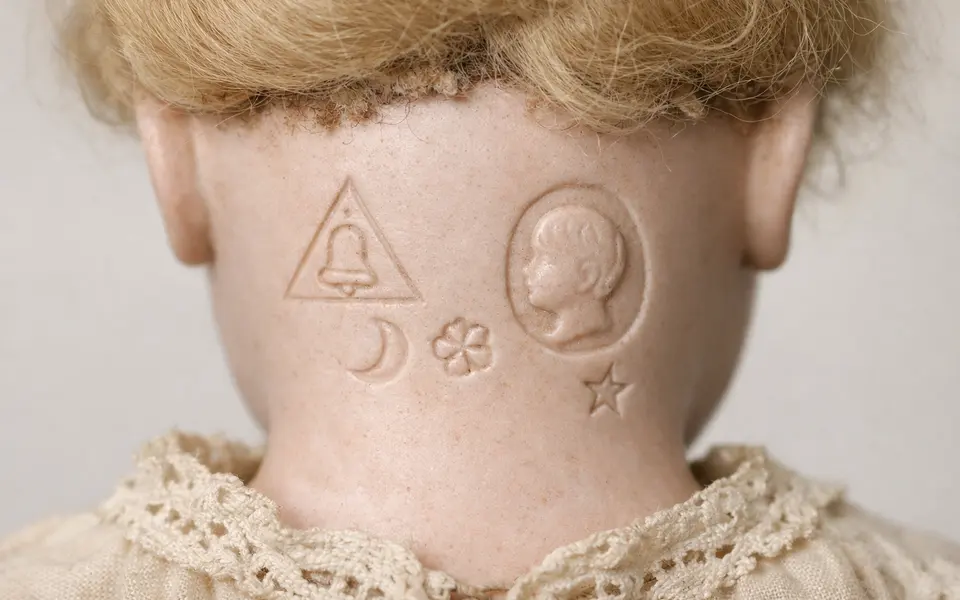 AI-generated close-up of invented symbols on a doll head, not actual maker marks.