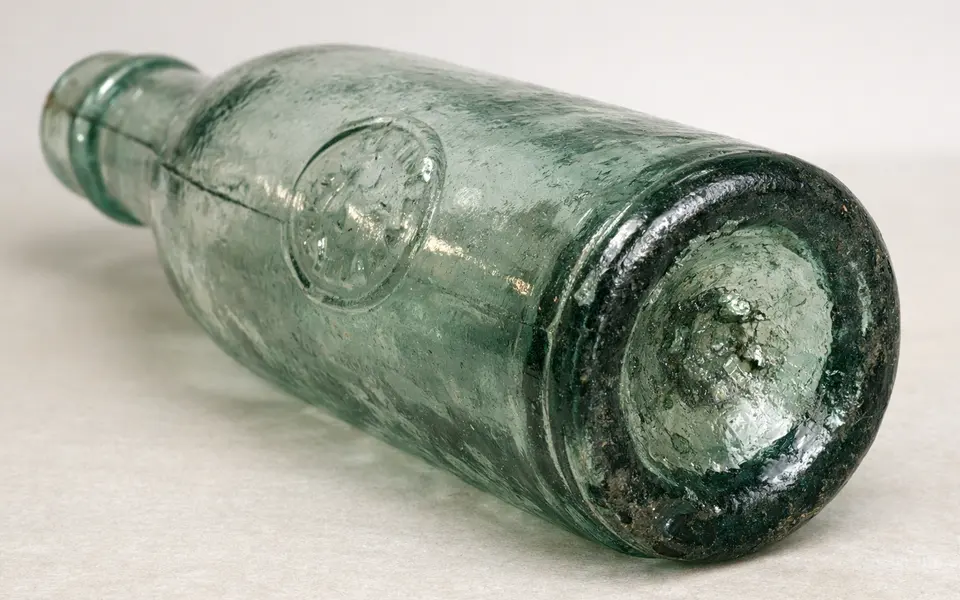 AI-generated close view of the base and embossed side of a green glass bottle.
